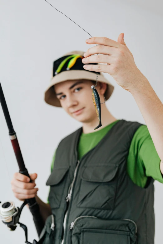 a man in a hat holding a fishing rod, a colorized photo, trending on pexels, teen elf, xqc, fish hooks, professional sports style