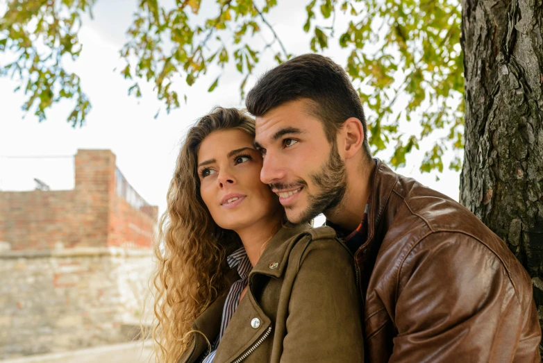 a man and a woman leaning against a tree, trending on pexels, renaissance, wearing brown leather jacket, redahair and attractive features, avatar image, spanish