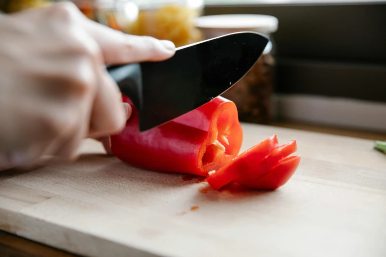a person cutting up a red pepper on a cutting board, by Julia Pishtar, highly upvoted, a folding knife, cutlery, crushed