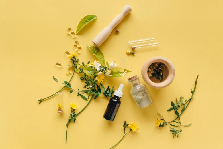 a bottle of essential oils and flowers on a yellow background, by Julia Pishtar, trending on pexels, pestle, adorned with all kind of plants, acupuncture treatment, yellow and black