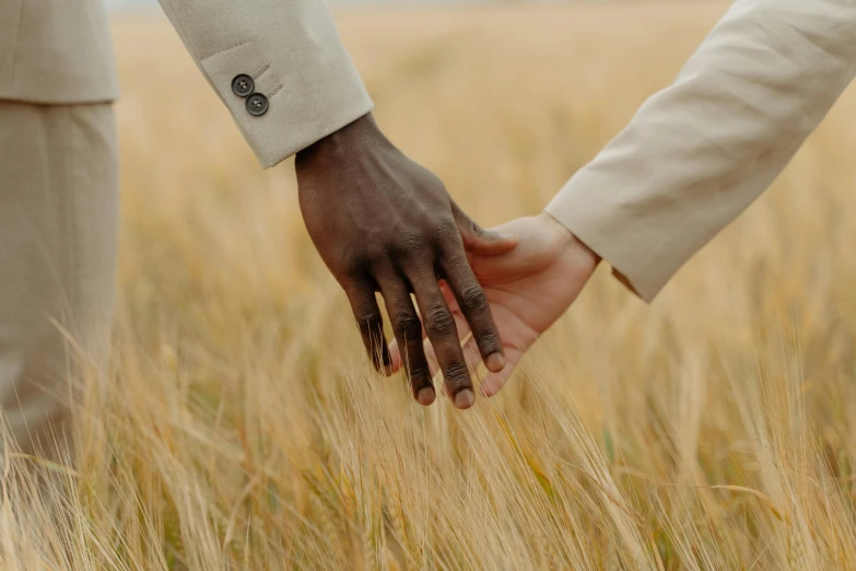 a man and a woman holding hands in a wheat field, a colorized photo, by Carey Morris, trending on unsplash, ivory and ebony, with brown skin, sophisticated hands // noir, hammershøi