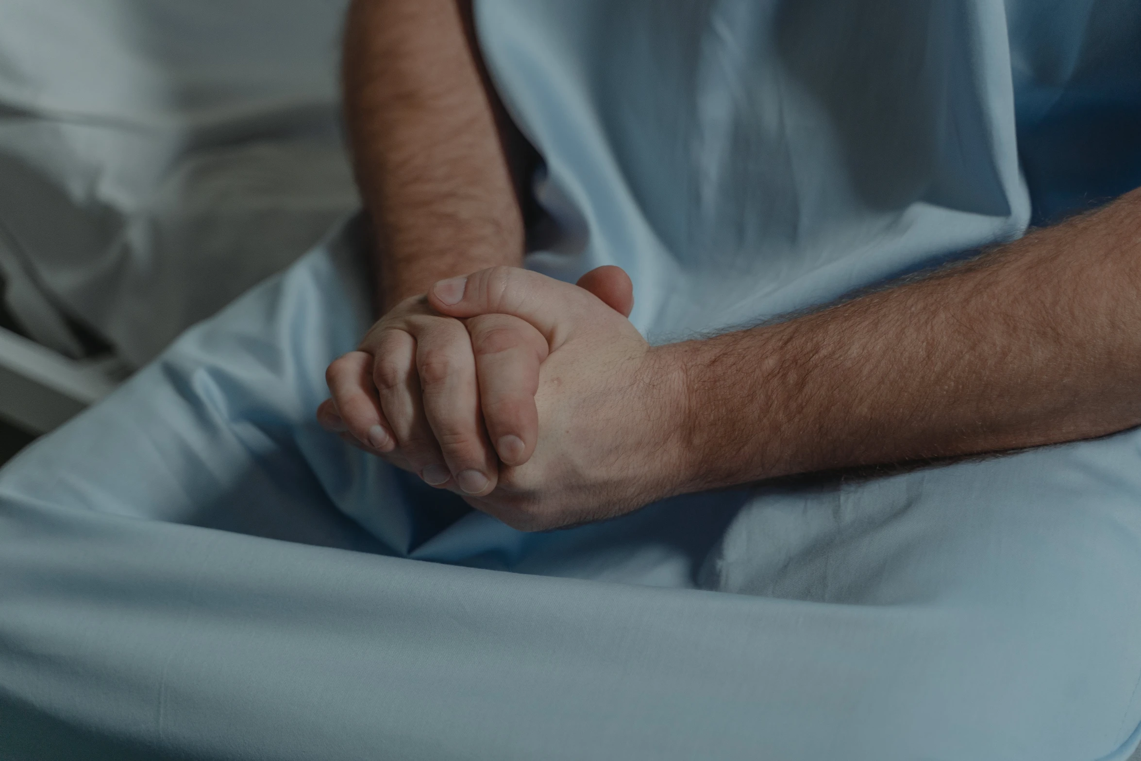 a man sitting in a hospital bed holding his hand, unsplash, renaissance, background image, multiple stories, blue, clinically depressed