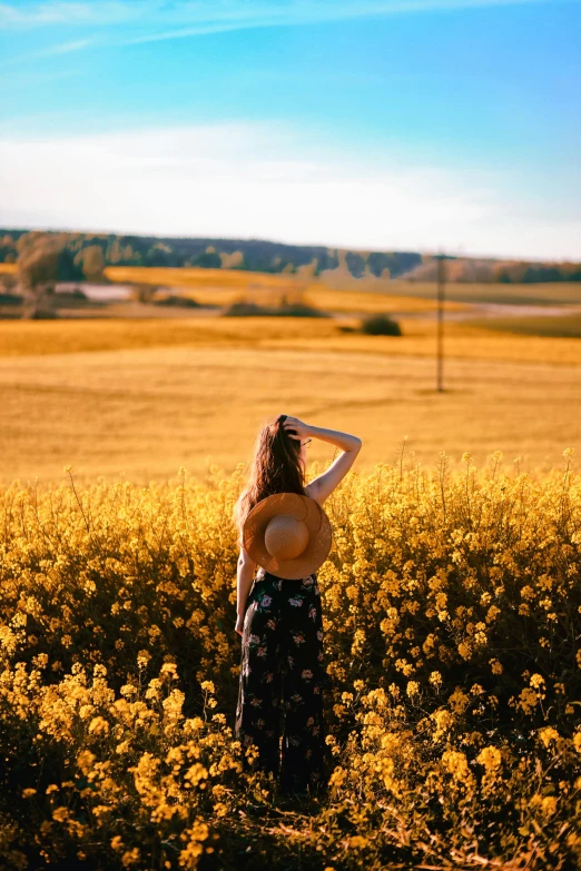 a woman standing in a field of yellow flowers, by Sven Erixson, pexels contest winner, looking onto the horizon, swedish countryside, warm glow, various posed