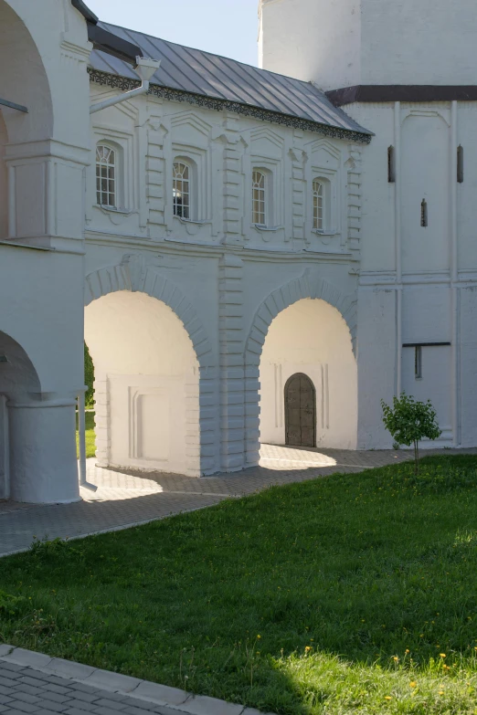 a large white building sitting on top of a lush green field, inspired by Konstantin Vasilyev, renaissance, there are archways, courtyard, white wall, kremlin