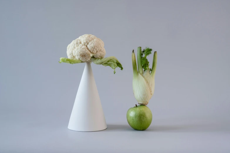 a white vase sitting next to a green apple, a surrealist sculpture, inspired by Robert Mapplethorpe, magic realism, lettuce, cone heads, with a long white, salad