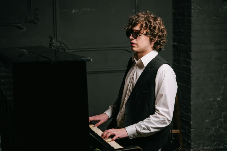 a man with curly hair playing a piano, inspired by Michael Ray Charles, wearing a suit and glasses, lachlan bailey, portrait image, performing