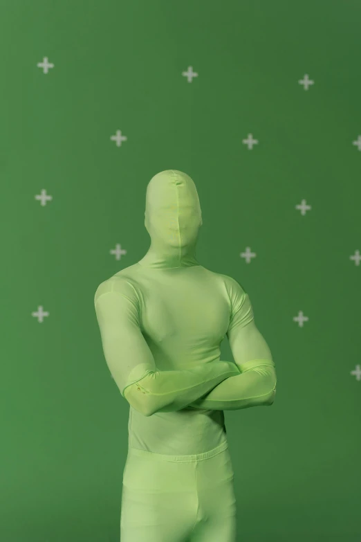 a man standing with his arms crossed in front of a green background, a hologram, trending on zbrush central, zentai suit, pale green background, 1 figure only, green facemask