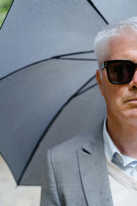 a man in a suit and sunglasses holding an umbrella, by Graham Forsythe, blinding white hair, jury, thumbnail, looking serious