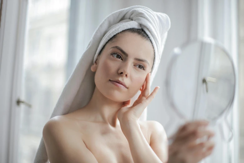 a woman with a towel on her head looking in a mirror, manuka, silicone skin, flawless features, smooth body features