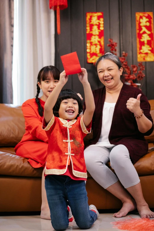 a woman and a child sitting on a couch, pexels contest winner, symbolism, wearing a red cheongsam, throwing cards in the air, square, wearing festive clothing