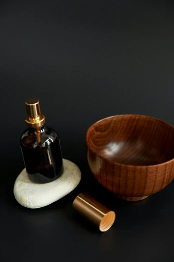 a wooden bowl sitting next to a wooden soap dispenser, a still life, inspired by Ceferí Olivé, unsplash, made of polished broze, perfume bottle, lustrous minerals, japanese collection product