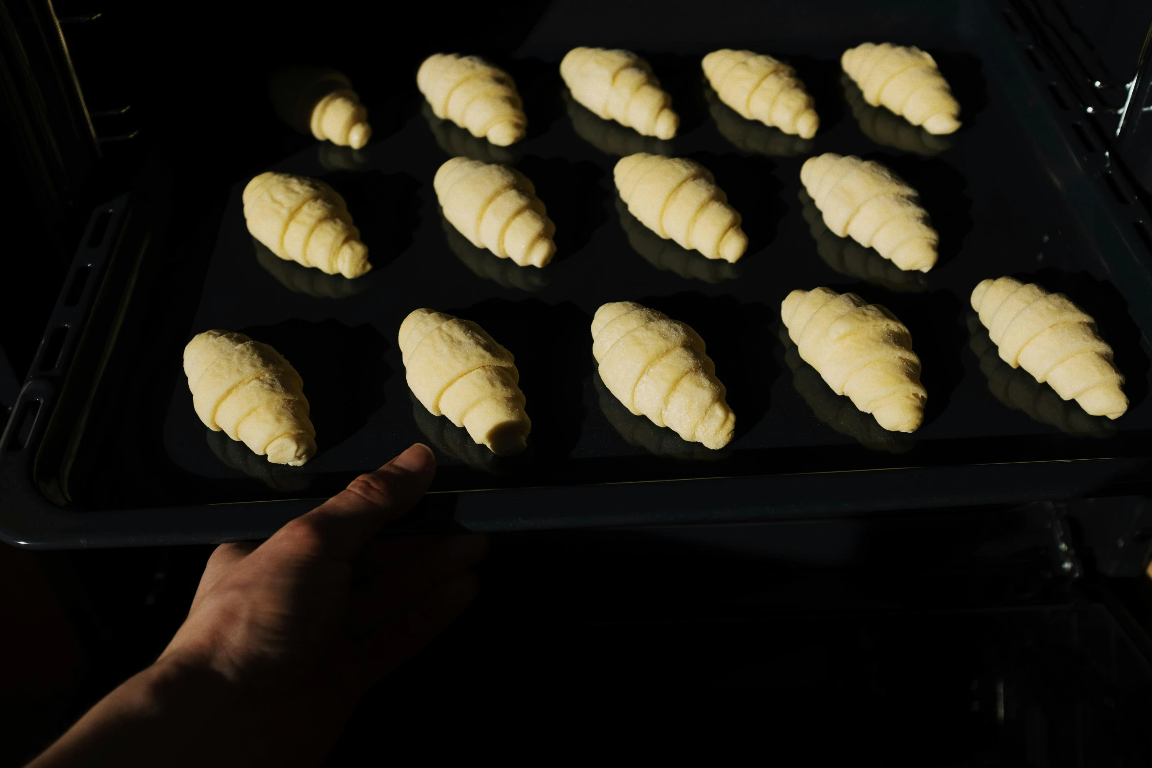 a person taking a tray of croissants out of the oven, inspired by Richmond Barthé, process art, on black background, cone heads, thumbnail, 1 0