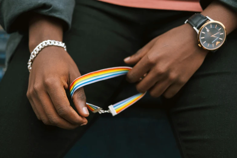 a close up of a person holding a wrist watch, an album cover, by Nina Hamnett, trending on unsplash, rainbow accents, medal, collar and leash, roygbiv