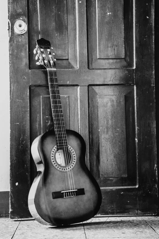 a black and white photo of a guitar in front of a door, uploaded, made of wood!!!!!, mateus 9 5