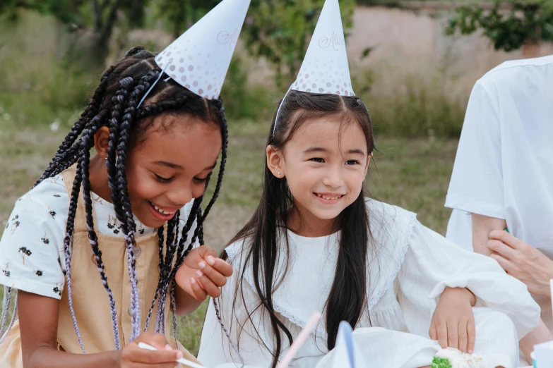 a group of children sitting at a table with a cake, pexels contest winner, party hats, white hanfu, avatar image, two girls