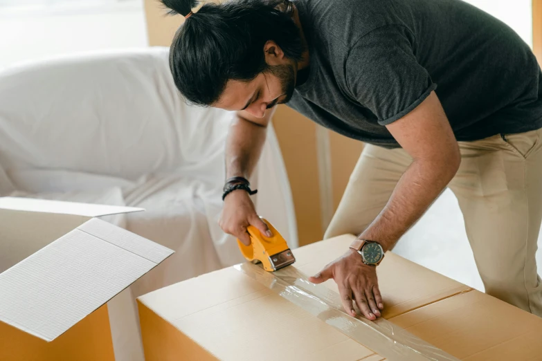 a man using a glue gun on a cardboard box, pexels contest winner, avatar image, beautiful photo, furniture, australian