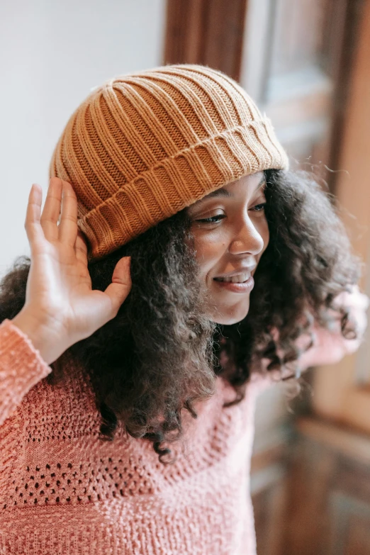 a woman in a pink sweater and a brown hat, trending on pexels, wavy hair yellow theme, beanie hat, sustainable materials, happy friend