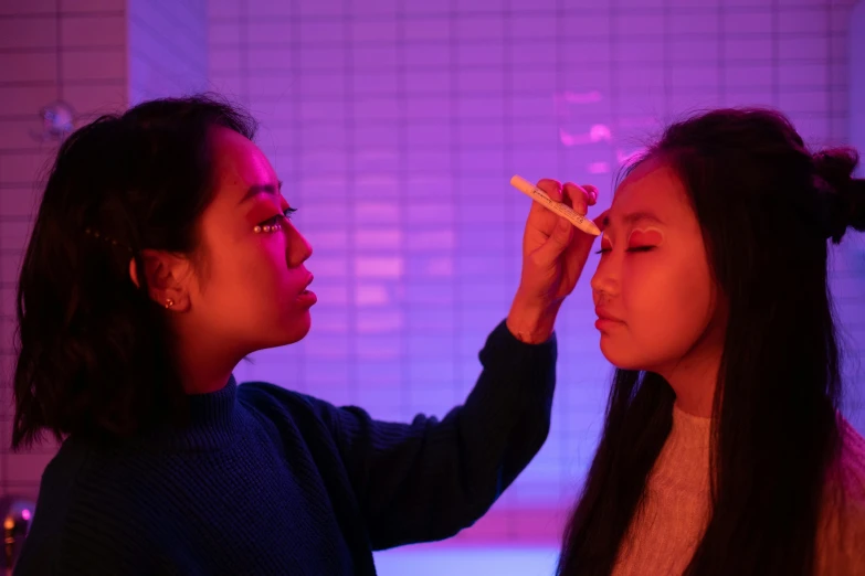 a woman putting makeup on another woman's face, inspired by Wang Duo, brightly lit pink room, mit technology review, aesthetic lighting, asian descent