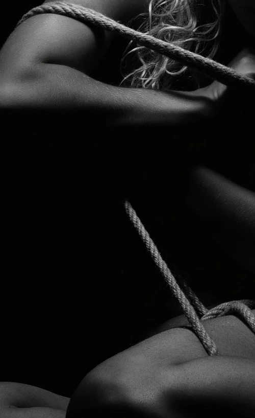 a black and white photo of a woman tied up, by Thomas Häfner, unsplash, conceptual art, on black paper, detail shot, black car, wearing dark maritime clothing