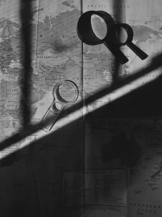 a pair of scissors sitting on top of a map, a black and white photo, by andrei riabovitchev, lights and shadows, magnifying glass, by joseph binder, a mysterious