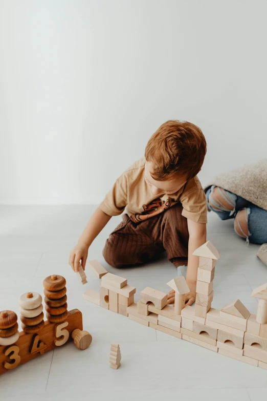 a little boy playing with wooden blocks on the floor, trending on unsplash, visual art, full body hero, designer product, earthy, toys