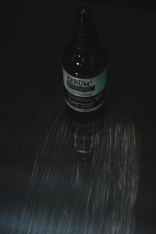 a bottle of liquid sitting on top of a table, inspired by Elsa Bleda, reddit, purism, hair texture, shot at dark with studio lights, extremely strong wind, smelling good