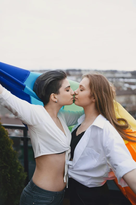 two women kissing each other while holding a rainbow flag, standing on rooftop, 👰 🏇 ❌ 🍃, andrea savchenko, profile image