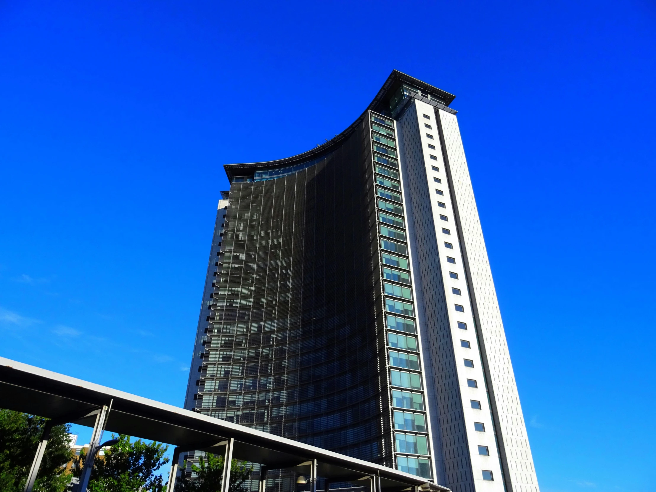 a tall building sitting on top of a lush green field, inspired by Tadao Ando, unsplash, bauhaus, coventry city centre, clear blue sky, gaming, cascading highrise