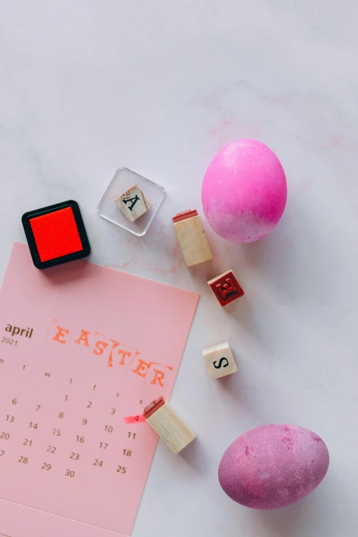 a pink calendar sitting on top of a white table, by Julia Pishtar, pexels contest winner, happening, holding easter eggs, rubber stamp, thumbnail, knolling