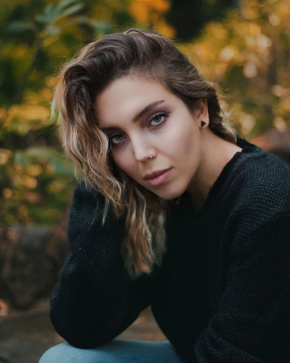 a beautiful young woman sitting on top of a wooden bench, inspired by Elsa Bleda, trending on unsplash, androgynous face, elizabeth olsen, wearing a black sweater, staring into the camera