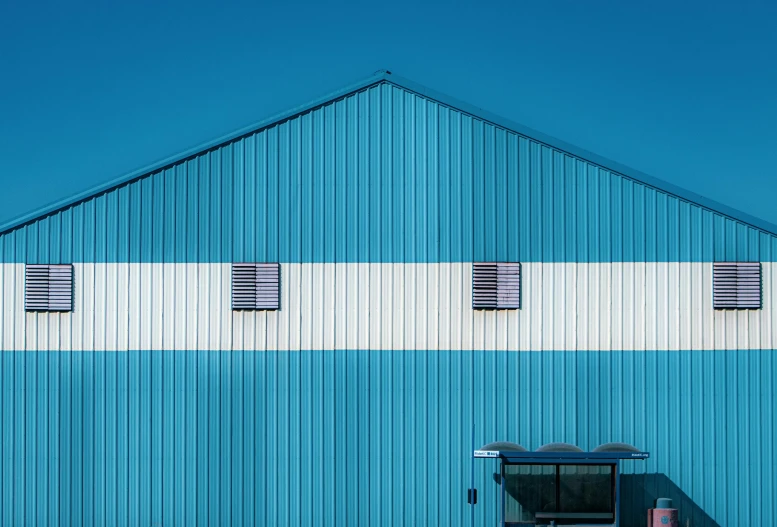 a blue building with a fire hydrant in front of it, a minimalist painting, by Jan Rustem, pexels contest winner, postminimalism, hangar, galvalume metal roofing, square lines, shot on sony a 7 iii