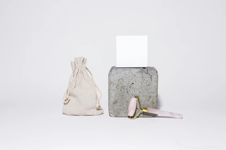 a pair of scissors sitting next to a bag, inspired by Eden Box, minimalism, pink concrete, occasional small rubble, product image, full product shot