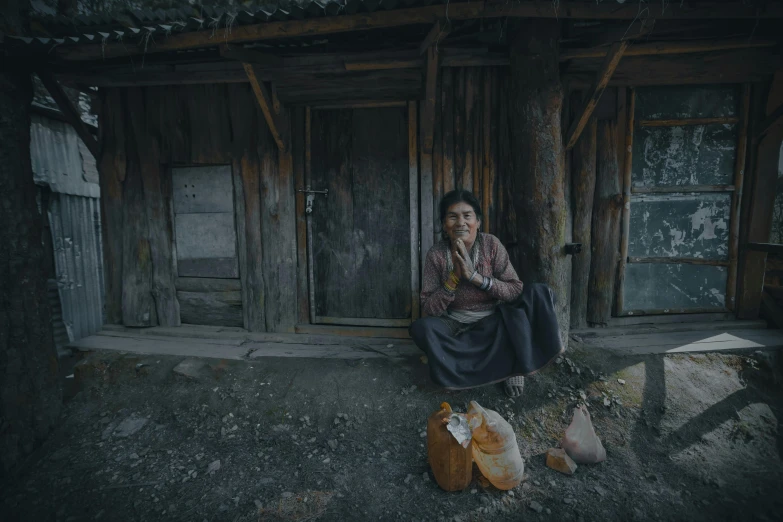 a woman sitting in front of a wooden building, hunger, award winning cinematic still, georgic, 8 k )