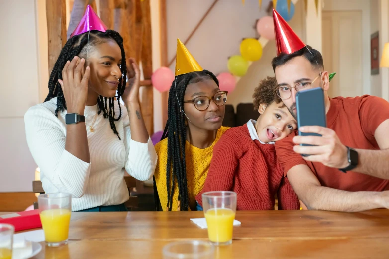 a group of people sitting around a wooden table, a portrait, pexels, happening, wearing a party hat, avatar image, smartphone photo, pals have a birthday party