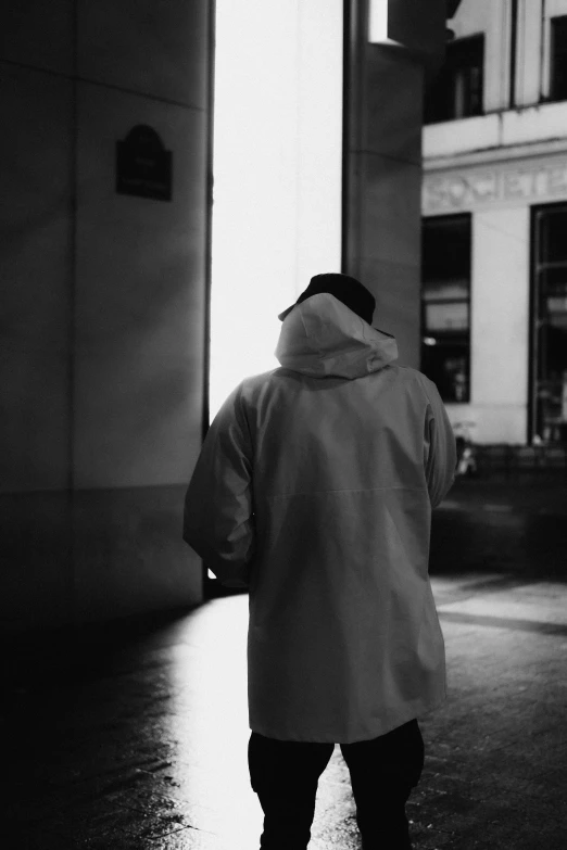 a black and white photo of a person on a skateboard, inspired by Louis Stettner, unsplash contest winner, realism, wearing a labcoat, obscured hooded person walking, about to enter doorframe, he wears a big coat