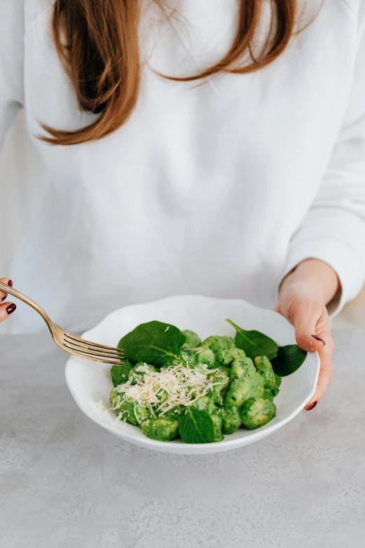 a close up of a person holding a bowl of food, light green, green and white, cutlery, lush green