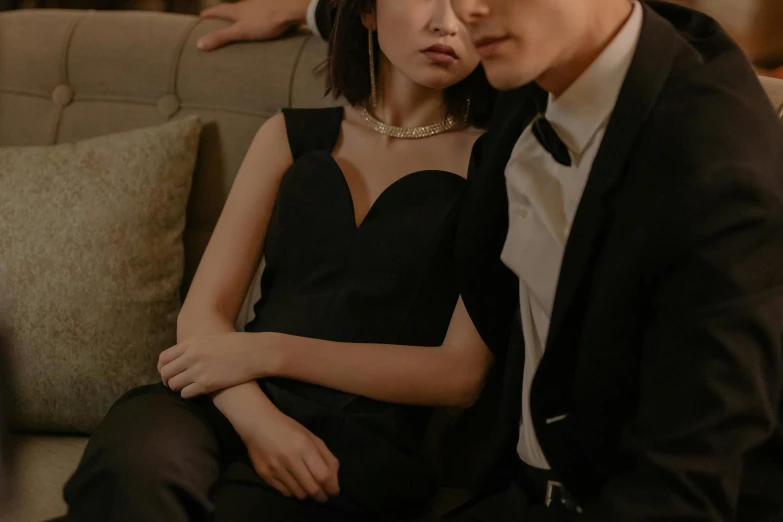 a man and a woman sitting on a couch, trending on pexels, diamonds around her neck, elegant japanese woman, black gown, romantic lead