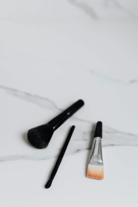 a couple of brushes sitting on top of a counter, trending on pexels, black eyeliner, marble, minimalistic drawing, realistic »