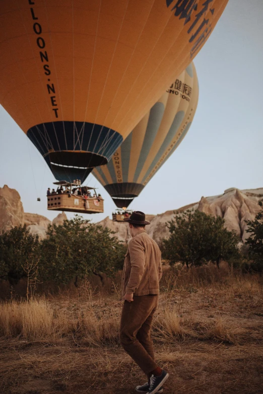 a man standing next to a hot air balloon, a picture, by irakli nadar, unsplash contest winner, instagram story, brown, turkey, wes anderson film