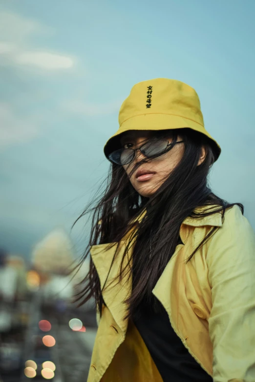 a woman in a yellow jacket and a yellow hat, inspired by Wang E, trending on pexels, female with long black hair, chillhop, icon, shades