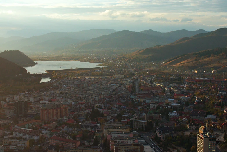 a bird's eye view of a city with mountains in the background, by Muggur, pexels contest winner, hurufiyya, lake baikal in the background, nice afternoon lighting, vallejo, ultrawide lens”