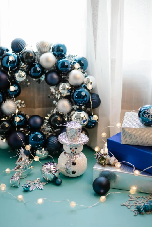 a christmas wreath sitting on top of a table next to presents, blue and silver, midnight-blue, artation, swarovski style