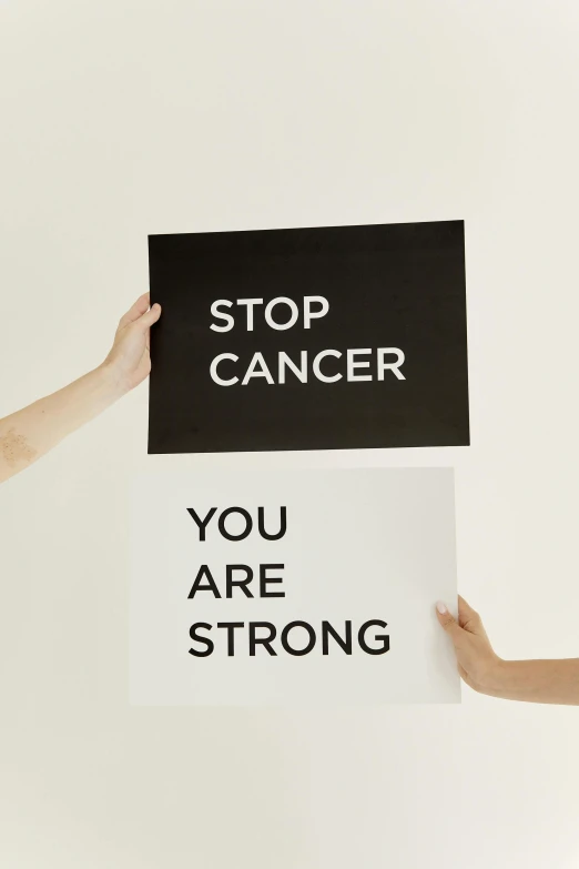 a woman holding a sign that says stop cancer you are strong, by Julia Pishtar, antipodeans, high - resolution scan, u