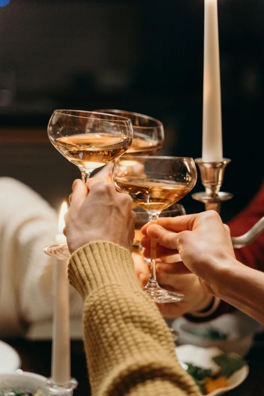 a group of people toasting with wine glasses, by Adam Marczyński, pexels, renaissance, holding a candle holder, champagne, home, winter