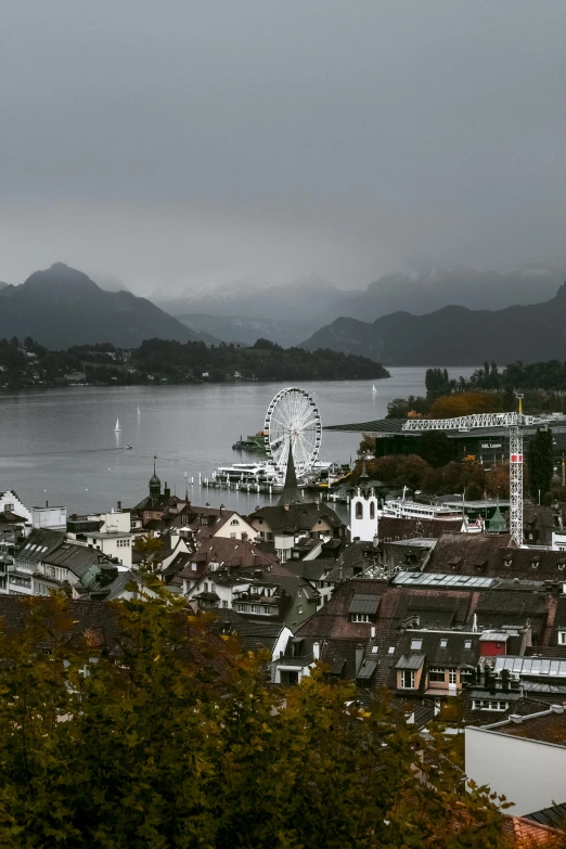 a view of a city with a ferris wheel in the distance, pexels contest winner, german romanticism, mountains and lakes, overcast gray skies, autum, a quaint