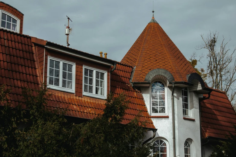 a clock that is on the side of a building, by Christen Dalsgaard, pexels contest winner, art nouveau, orange roof, suburban home, lead - covered spire, view from back