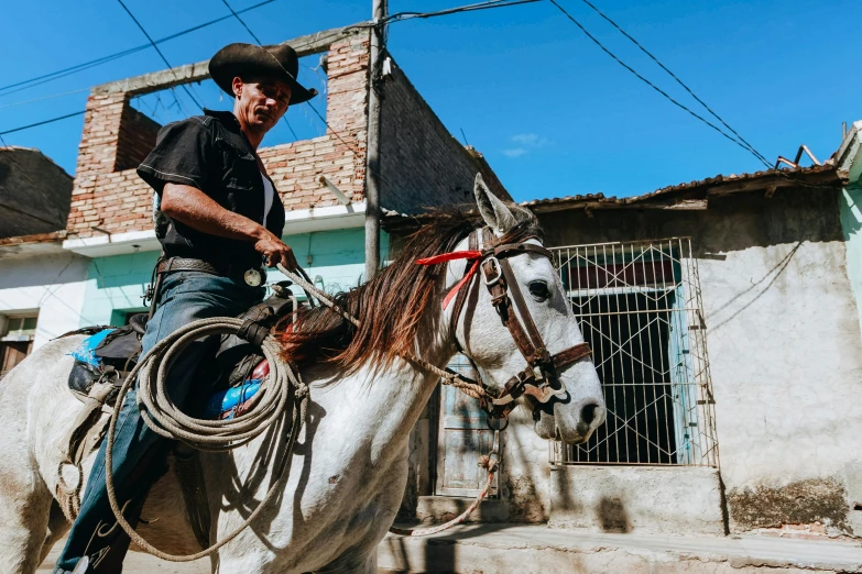 a man riding on the back of a white horse, pexels contest winner, standing in a township street, mexican vaquero, thumbnail, jenna barton