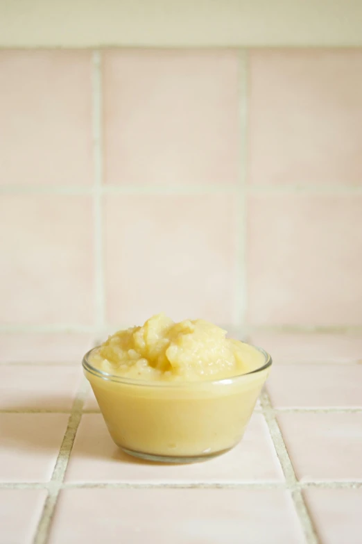 a close up of a bowl of food on a tiled floor, by Morris Kestelman, mashed potatoes, yellow translucent lace, ignant, detailed product image