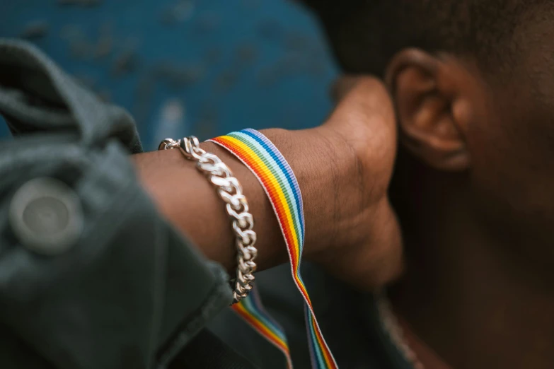 a close up of a person wearing a bracelet, trending on pexels, process art, lgbt, diverse, thumbnail, ribbon