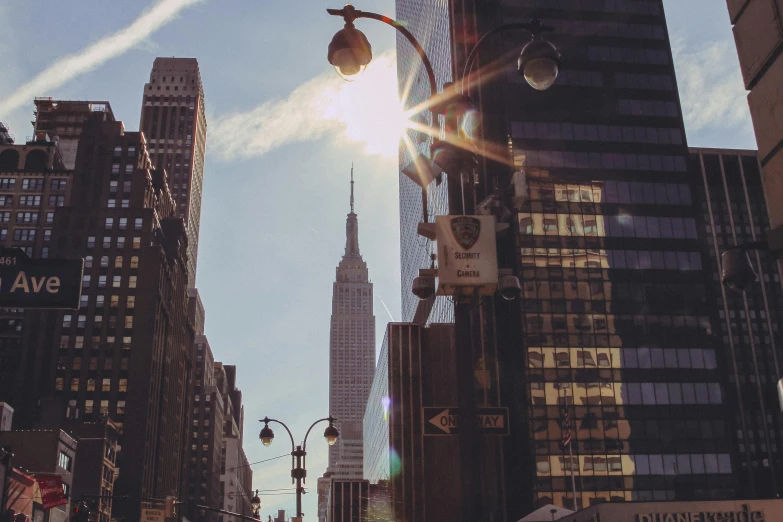 a city street filled with lots of tall buildings, pexels contest winner, modernism, empire state building, sunlight shining through, promo image, streetlamps